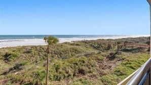 A beach view with a wooden boardwalk and sparse vegetation.