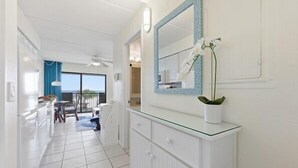 A modern bathroom with a glass vanity, a large mirror, and a potted orchid.