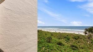 Vista a la playa con un muro blanco y cielo despejado.
