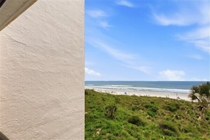 A beach view with a white wall and a clear sky.