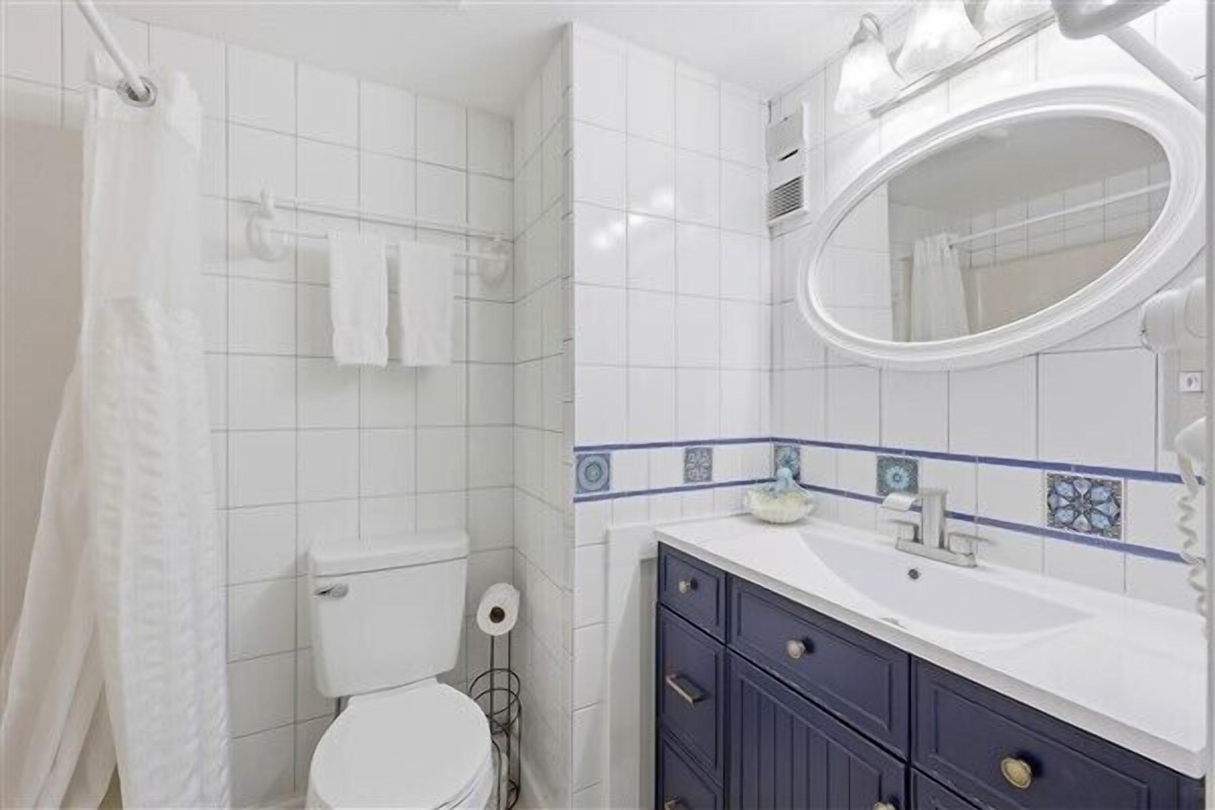 A bathroom with a toilet, sink, mirror, and shower curtain.