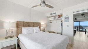 Un dormitorio con una cama grande, un ventilador de techo, una mesita de noche y vistas al balcón.