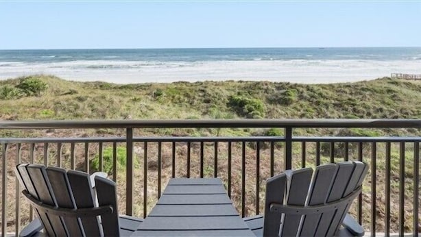 Un balcon avec deux fauteuils Adirondack donnant sur une plage.