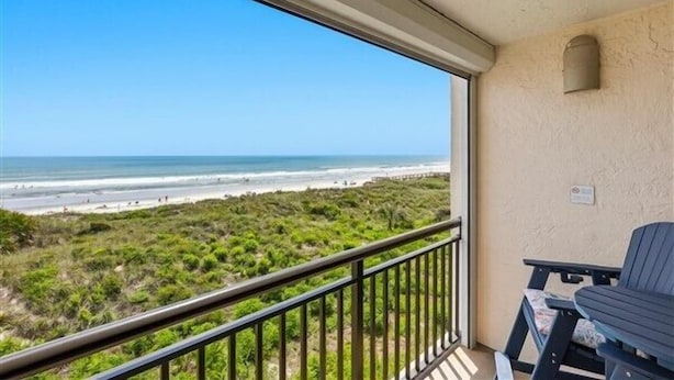 A balcony with a view of the beach, a chair, and a table. - Beacher's Oceanfront Balcony Suite with Onsite Front desk and staff (St. Augustine)