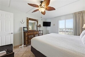A hotel room with a bed, a dresser, a ceiling fan, a TV, and a window with curtains. - Beacher's Oceanfront Balcony Suite with Onsite Front desk and staff (St. Augustine)