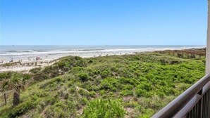 A beach view with a grassy area and a clear sky.