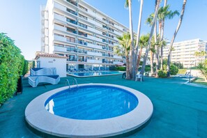 A hotel with a swimming pool, palm trees, and a large building in the background. - Carole Apartment,  with pool in the Port d'Alcudia, for two guests (Alcúdia)