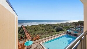 A pool with a view of the beach and a slide.