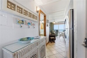 A hallway with a wicker console table, decorative wall art, and a view to a balcony with outdoor seating. - Beacher's Oceanfront Balcony Suite with Onsite Front desk and staff (St. Augustine)