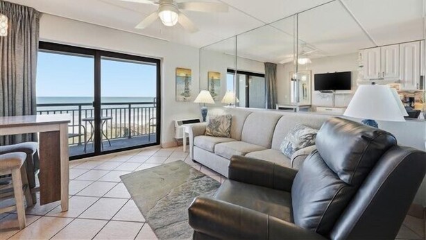 A modern living room with a sofa, a dining table, and a view of the ocean.