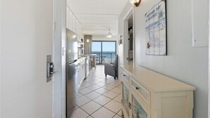 A narrow hallway with a kitchen area, a dining area, and a balcony with a view.