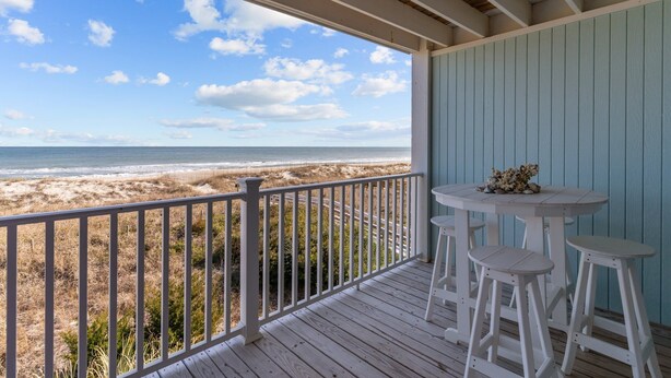 A wooden deck with a view of the beach and ocean.