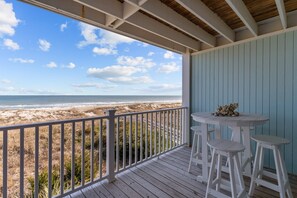 Una terraza de madera con vista a la playa y al océano.