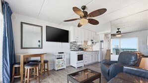 Un salon moderne avec un canapé, une table basse, un téléviseur et un ventilateur de plafond.