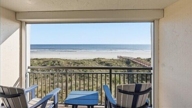 A balcony with a view of the beach, featuring two chairs and a small table. - Beacher's Oceanfront Balcony Suite with Onsite Front desk and staff (St. Augustine)