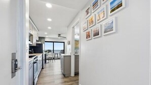 A modern kitchen with white cabinets, a wooden floor, and a dining area with a view. - Beacher's Oceanfront Balcony Suite with Onsite Front desk and staff (St. Augustine)
