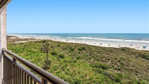 A beach view from a balcony with a clear sky.