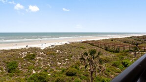 A beach view with a wooden boardwalk, sandy beach, and sparse vegetation. - Beacher's Oceanfront Balcony Suite with Onsite Front desk and staff (St. Augustine)