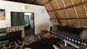 A room with a thatched roof, a sofa set, a dining table, and a patterned floor. - Nuru Ya Erika Villas (Malindi)