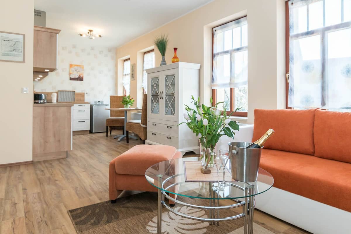 Una sala de estar moderna con una mesa de centro de vidrio, un sofá y una zona de comedor con una cocina al fondo.