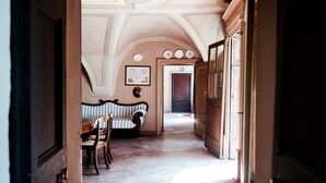 A hallway with a striped bench, a wooden table, and a door leading to another room. - Solimago Dimora Storica (Solferino)