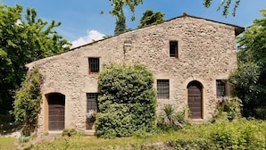 A rustic stone building with arched doorways and windows, surrounded by greenery. - Solimago Dimora Storica (Solferino)