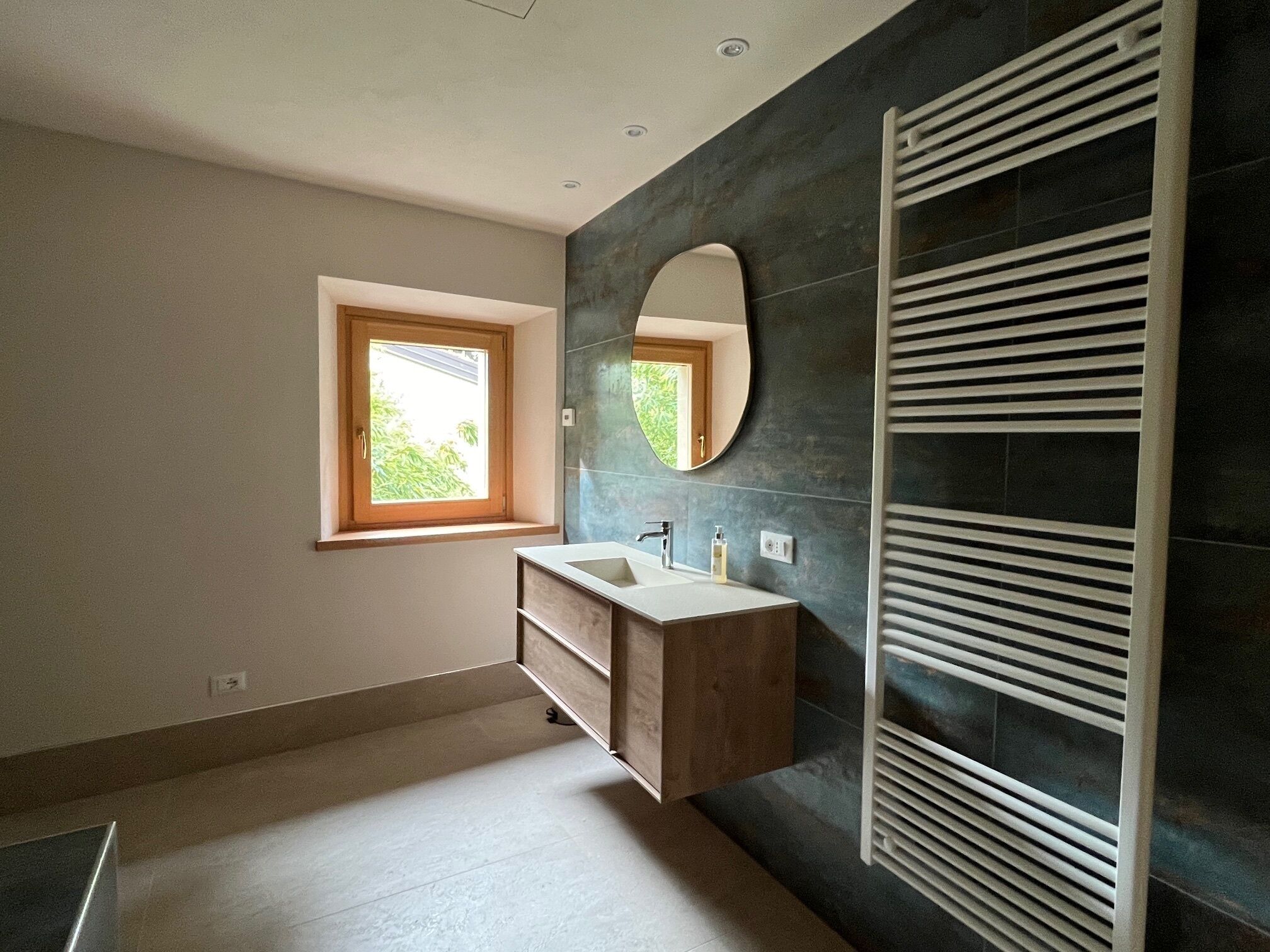 A modern bathroom with a window, a vanity with a mirror, and a wall-mounted towel rack.