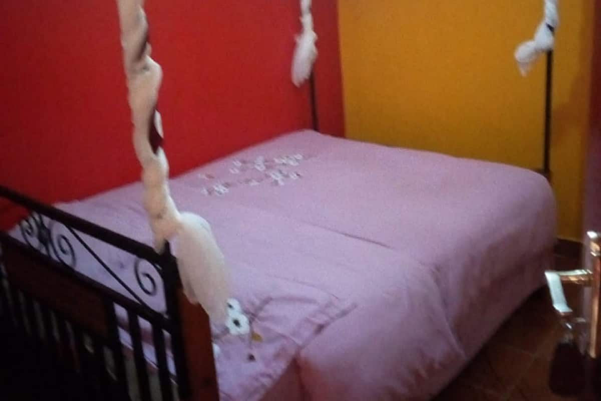 A single bed with a pink bedspread and a red and white striped canopy.