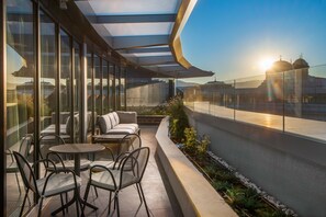 A rooftop terrace with glass walls, outdoor seating, and a view of the cityscape. - Hyatt Regency Sofia (Sofia)