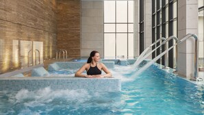 A woman relaxing in a spa bath with a view of the city through large windows. - Hyatt Regency Sofia (Sofia)