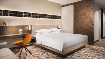 Une chambre d’hôtel moderne avec un grand lit, un bureau avec une chaise et un sol à motifs.
