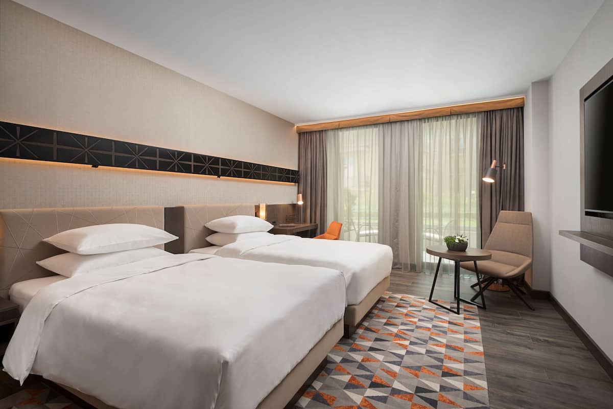 Ein Hotelzimmer mit zwei Betten, einem kleinen Tisch, einem Stuhl und einem Fernseher.