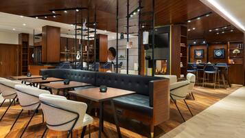 Ein modernes Interieur mit Holzbalkendecke, einer schwarzen Ledersofa und einer Bar mit Hockern.