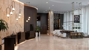 A modern hotel lobby with a reception desk, seating area, and a large window with curtains. - Hyatt Regency Sofia (Sofia)
