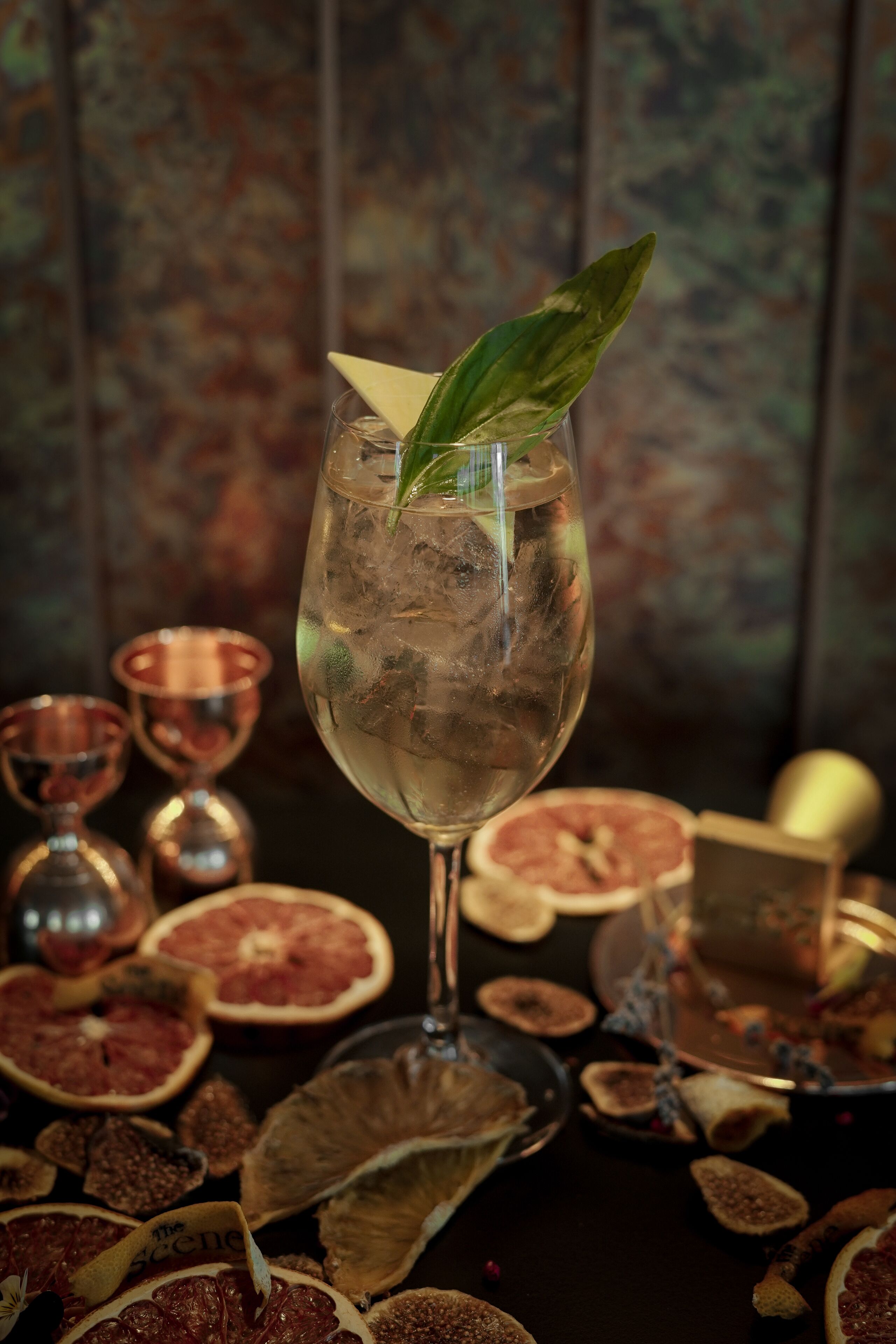 A glass of drink with a leaf garnish, surrounded by dried fruits and a decorative box.