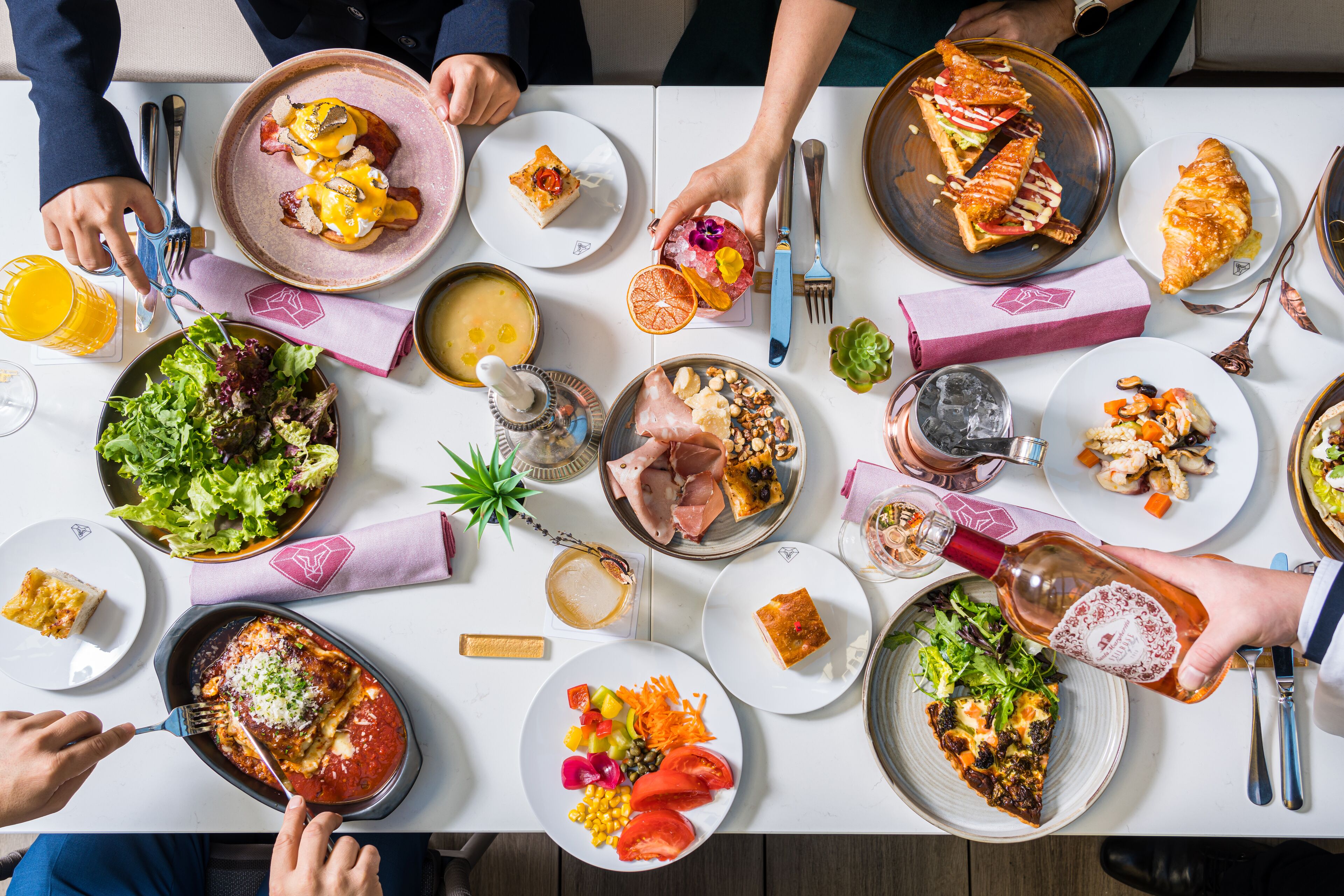 Een eettafel met verschillende gerechten, waaronder pizza, salade en een bord vlees.