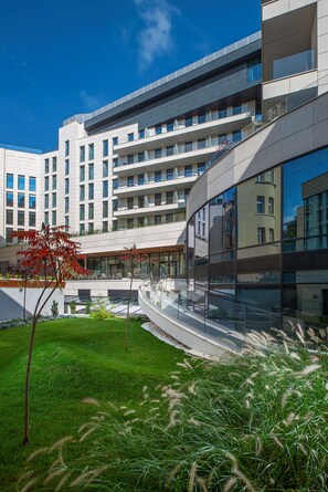 A modern hotel with multiple floors, large windows, and a well-maintained outdoor area with grass and plants.