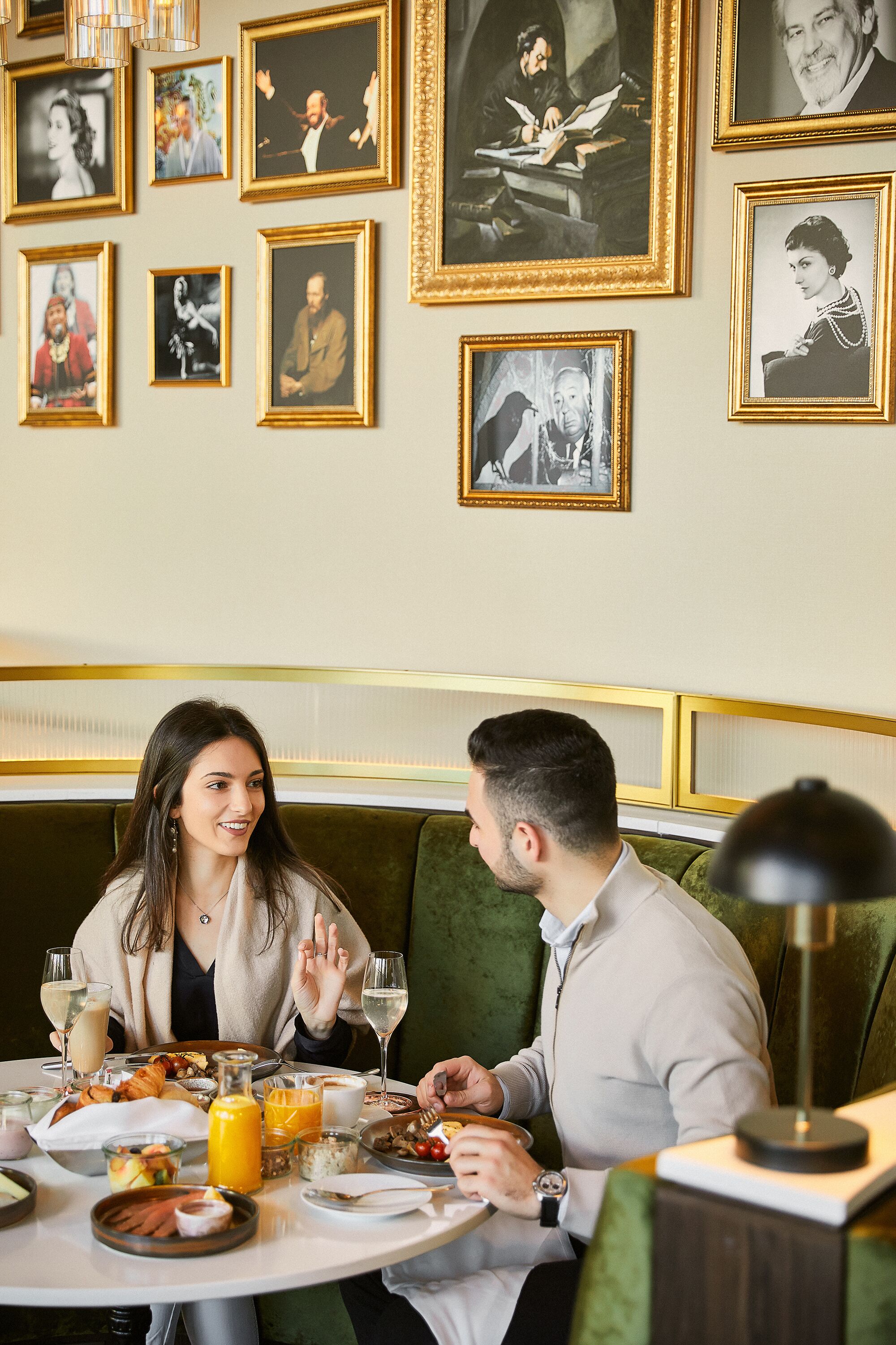 Ein Essbereich mit einem runden Tisch, gedeckt für zwei Personen, umgeben von gerahmten Fotos an der Wand.
