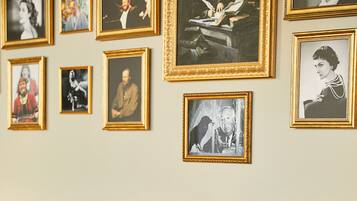 A dining area with a round table set for two, surrounded by framed photographs on the wall.