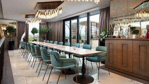 A modern dining area with a long table, teal chairs, and a chandelier. - Hyatt Regency Sofia (Sofia)