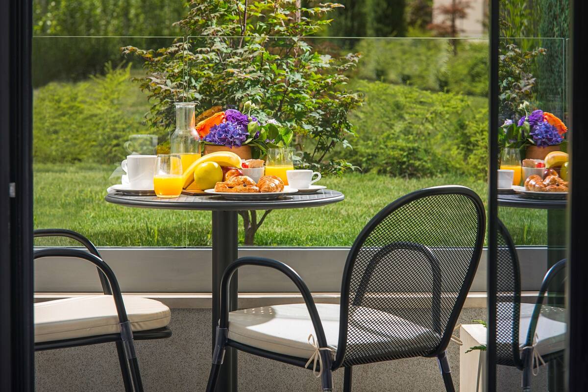 Ein gedeckter Tisch mit Frühstücksangeboten, ein Topfpflanze und Blick auf eine grüne Landschaft.