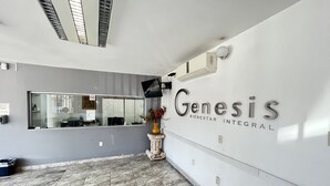Ett väntrum med ett stort spegel, en väggmonterad skylt med texten ”Genesis Bienestar Integral” och ett klinkergolv.