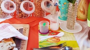 A breakfast buffet with various food items, utensils, and a flower centerpiece. - Pension Fischerhaus (Trassenheide)
