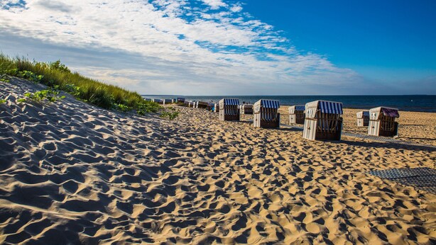 A sandy beach with beach huts and a clear sky. - Pension Fischerhaus (Trassenheide)