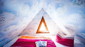 A cozy, triangular tent-like room with a bed, pillows, and a window. - Pension Fischerhaus (Trassenheide)