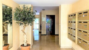A hallway with a potted tree, mailboxes, and a door leading to another room. - Large and Quiet Studio with Balcony (Cannes)
