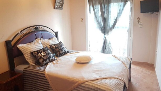 Cama bem arrumada com roupa de cama listrada, um travesseiro decorativo e uma mesa de cabeceira com abajur.