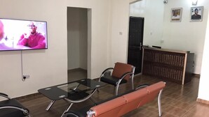 Un área de espera con mostrador de recepción, televisor y disposición de asientos.