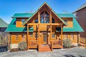 A log cabin with a green roof, a porch with railings, and a sign that reads "King of the Mountain."