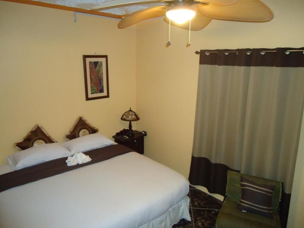A hotel room with a bed, a nightstand, a lamp, a chair, and a window with curtains.